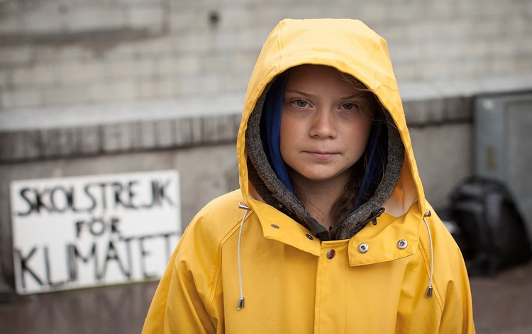 Greta Thunberg in front of a sign saying Skolstrejk för klimatet