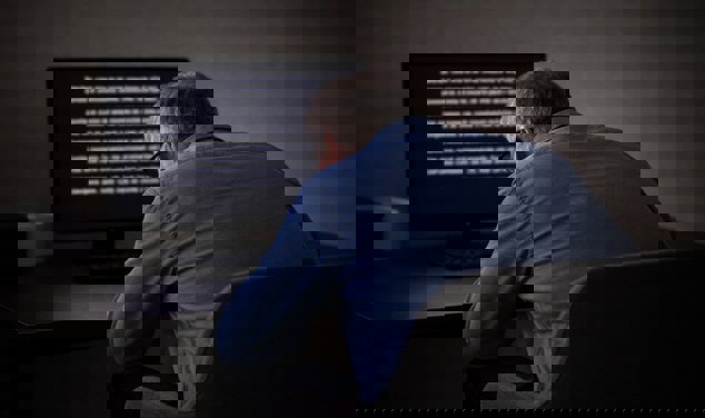 Äldre man som sitter framåtlutad mot datorskärm